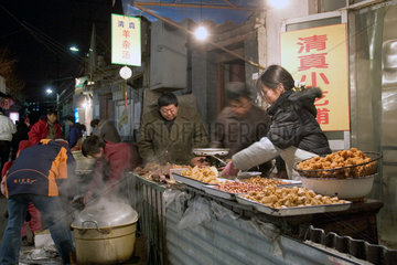 Peking  Haendlerin auf einem Markt bereitet Essen zu
