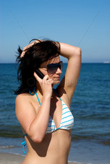 Ahrenshoop  Deutschland  eine junge Frau telefoniert am Strand