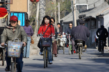 Peking  Menschen auf Fahrraedern und Mopeds