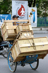 Vietnam  mit Kisten ueberladene Fahrradrikscha in Hue