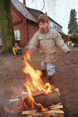 Junge haelt eine Hand ans Feuer  Norddeutschland
