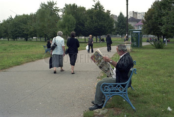 Mann liest Zeitung auf einer Bank im Izvor-Park  Bukarest  Rumaenien
