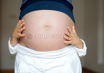 Berlin  Deutschland  Kinderhaende auf dem schwangeren Bauch der Mutter