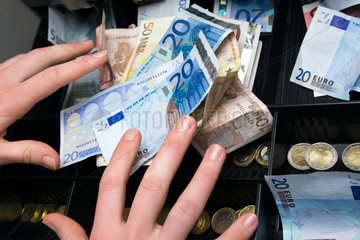 Berlin  Deutschland  Haende greifen nach Geld in der Kasse
