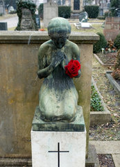 Freiburg  Deutschland  eine trauernde Grabfigur mit roter Rose auf einem Friedhof