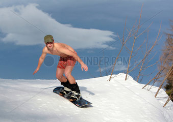 Krippenbrunn  Oesterreich  junger Mann in Boxershorts faehrt Snowboard