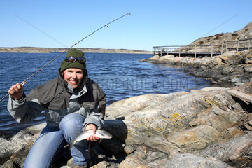 Suedschweden  Frau mit frisch gefangenem Fisch in den Schaeren