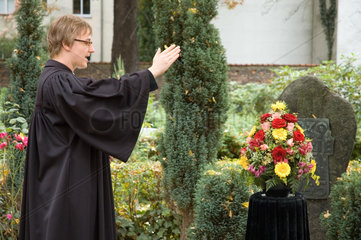 Berlin  Deutschland  Pastor auf einem Friedhof vor einem Familiengrab