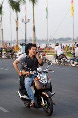 Phnom Penh  Kambodscha  ein junger Mann telefoniert beim Fahren auf seinem Motorrad