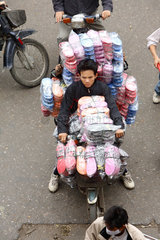 Eine Schuhverkaefer transportiert hunderte neuer Sandalen auf seinem Moped  Hanoi