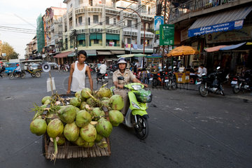 Phnom Penh  Kambodscha  Polizistin beobachtet einen Strassenhaendler mit Kokosnuessen