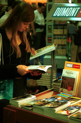 Ein Maedchen schmoeckert in einem Buch auf der Frankfurter Buchmesse