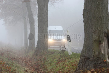 Blankenfelde  Deutschland  Autoverkehr auf einer Landstrasse bei Nebel