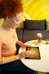 Hamburg  Deutschland  Frau sitzt mit ihrem iPad 2 in einem Cafe und spielt ein Game