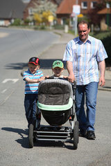 Koehn  Vater mit seinen Kindern und einem Kinderwagen unterwegs