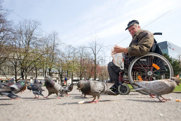 Berlin  Deutschland  ein Mann im Rollstuhl fuettert Tauben am Alexanderplatz