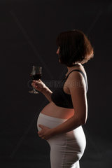Freiburg  Deutschland  eine schwangere Frau mit einem Glas Rotwein