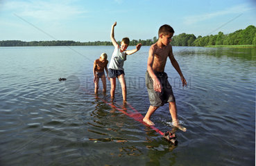 Drei Jungen spielen in einem See  Litauen