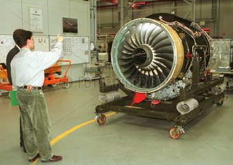Ein Mitarbeiter (Ingenieur) redet mit einem anderen Mann ueber ein Triebwerk bei Rolls-Royce Deutschland in Dahlewitz  Brandenburg.