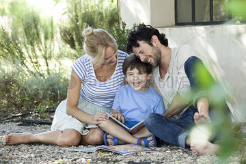 Parents reading book with child