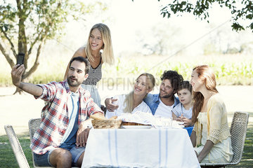 Family posing for a group photo while picnicking outdoors