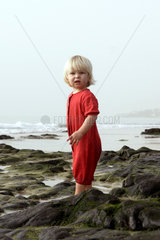 Pajara  ein kleines Kind steht mit erstauntem Gesicht am Strand