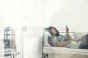 Woman lying on sofa  listening to MP3 player