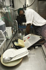 Worker washing dishes in commercial kitchen