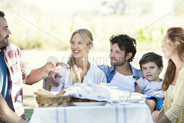Extended family eating meal and talking together outdoors