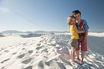 Young siblings standing on dune at White Sands National Monument  New Mexico  USA