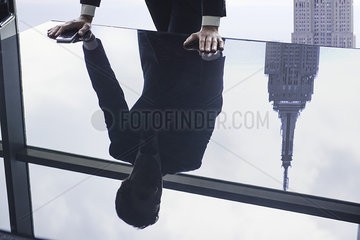 Businessman leaning against table  reflection in glass top