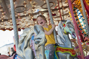 Little girl riding on carousel