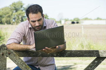 Farmer using laptop while out in field