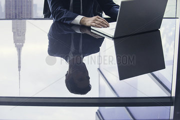 Businessman using laptop computer  reflection on glass top table