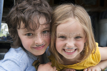 Young siblings wearing fake mustaches  portrait