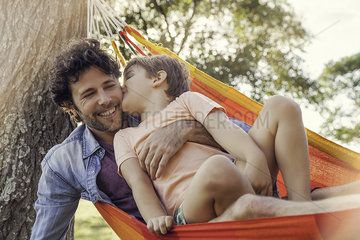 Father and son relaxing together in hammock