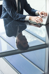 Businessman using laptop computer  reflection on glass top table