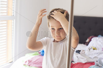 Boy fixing hair in front of mirror