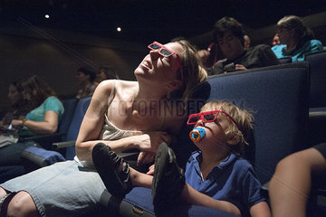 Mother and toddler son watching 3-D movie in theater