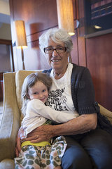 Grandmother and granddaughter embracing in chair  portrait
