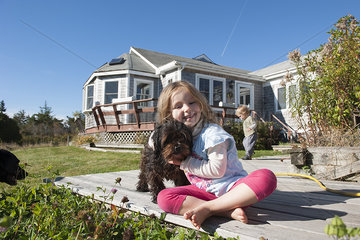 Little girl sitting on deck with pet dog