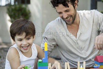 Father and son laughing while playing with toys