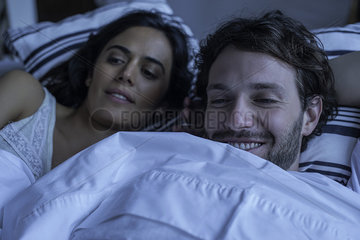 Couple watching tv together in bed