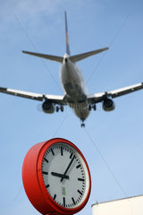 Berlin  Deutschland  ein tief fliegendes Flugzeug fliegt ueber eine Uhr