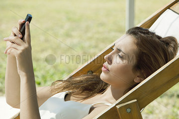 Young woman looking at smartphone while sunbathing