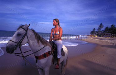Maedchen auf einem Pferd an der Kueste in Brasilien
