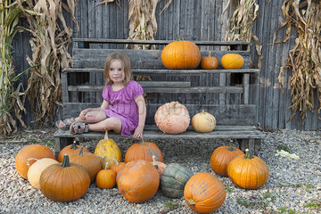 Girl sitting with a large assortment of pumpkins