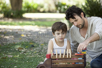 Father and son playing with toys in backyard