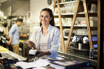 Woman using credit card reader at restaurant