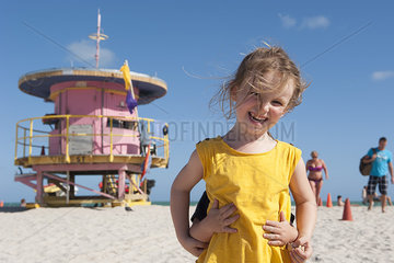 Little girl at the beach with younger brother hiding behind her